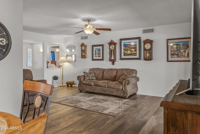 living room featuring ceiling fan, wood-type flooring, and a textured ceiling