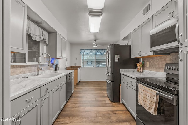 kitchen with sink, ceiling fan, gray cabinets, light wood-type flooring, and stainless steel appliances