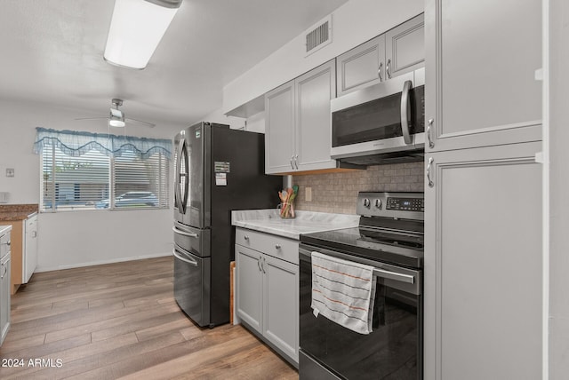 kitchen featuring appliances with stainless steel finishes, light wood-type flooring, tasteful backsplash, and ceiling fan