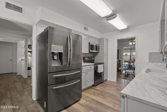 kitchen with decorative backsplash, light hardwood / wood-style floors, sink, and stainless steel appliances