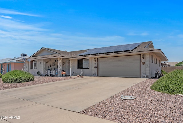 single story home featuring a porch, solar panels, and a garage