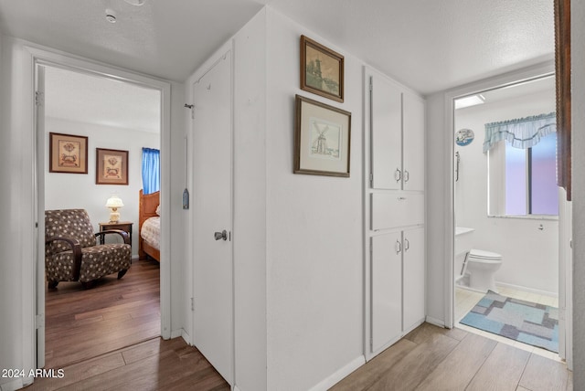 hall with a textured ceiling and light hardwood / wood-style floors