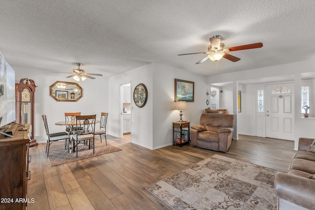 living room featuring a textured ceiling, hardwood / wood-style flooring, and ceiling fan