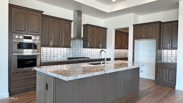 16777 W Sheila Ln, Goodyear, AZ 85395 - kitchen featuring stainless steel appliances, wall chimney exhaust hood, dark wood-style flooring, and decorative backsplash