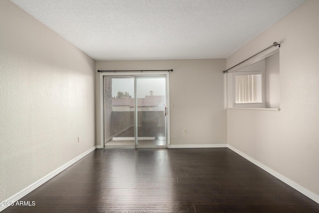 empty room featuring a textured ceiling, baseboards, and wood finished floors