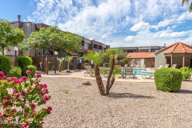 view of community featuring a residential view, a patio, a swimming pool, and fence