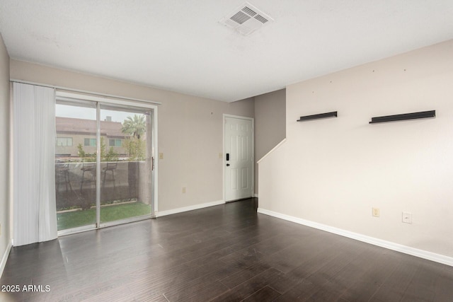 spare room with baseboards, visible vents, and wood finished floors