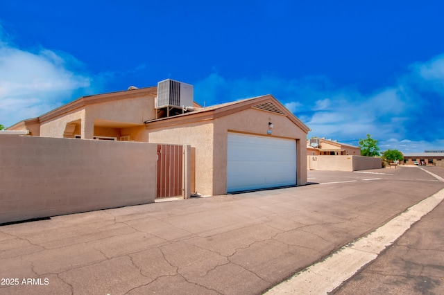 view of front of home featuring fence, central AC unit, a gate, and stucco siding