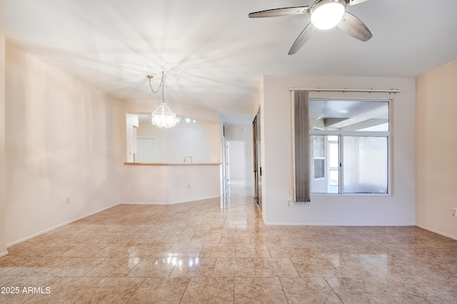 unfurnished room with baseboards and ceiling fan with notable chandelier