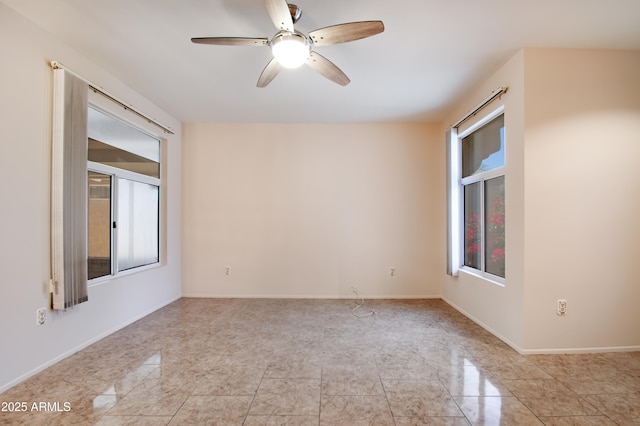 spare room with ceiling fan and baseboards
