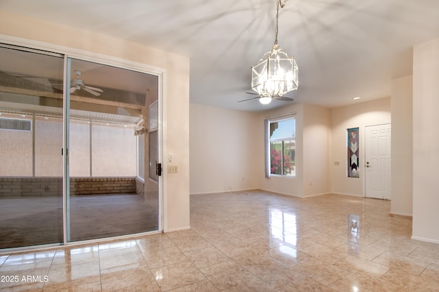 interior space featuring baseboards and ceiling fan with notable chandelier