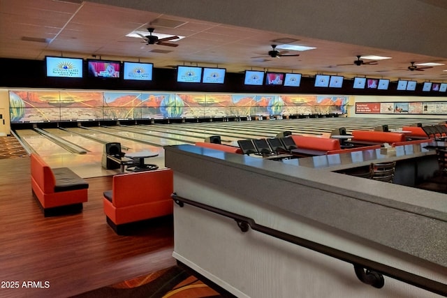 rec room featuring a drop ceiling, wood finished floors, and bowling