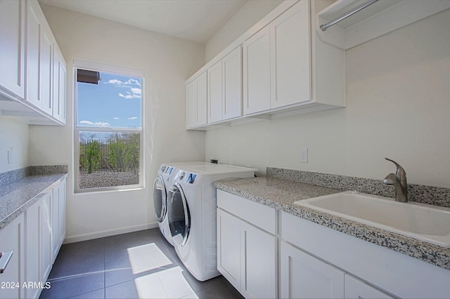 clothes washing area featuring washer and clothes dryer, dark tile floors, sink, and cabinets