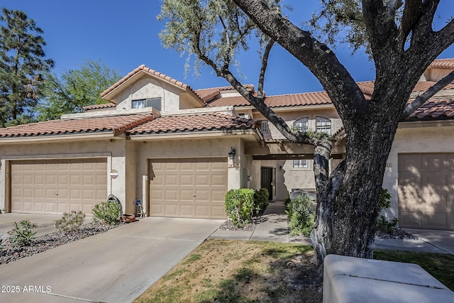 view of front facade with an attached garage, stucco siding, a tile roof, and concrete driveway