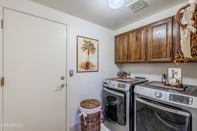 clothes washing area with washer and dryer, visible vents, and cabinet space