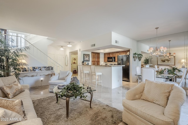 living area featuring visible vents, marble finish floor, stairs, and a notable chandelier