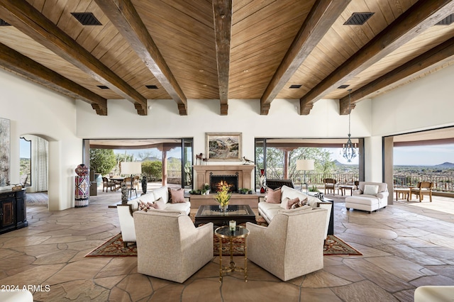 living room featuring beamed ceiling, a towering ceiling, an inviting chandelier, and wood ceiling