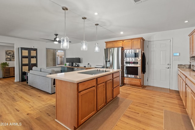 kitchen with stainless steel appliances, decorative light fixtures, ceiling fan, light wood-type flooring, and a kitchen island