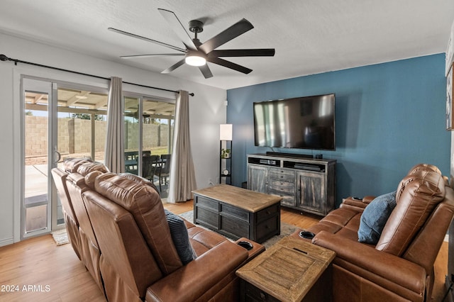 living room featuring light wood-type flooring, ceiling fan, and a textured ceiling