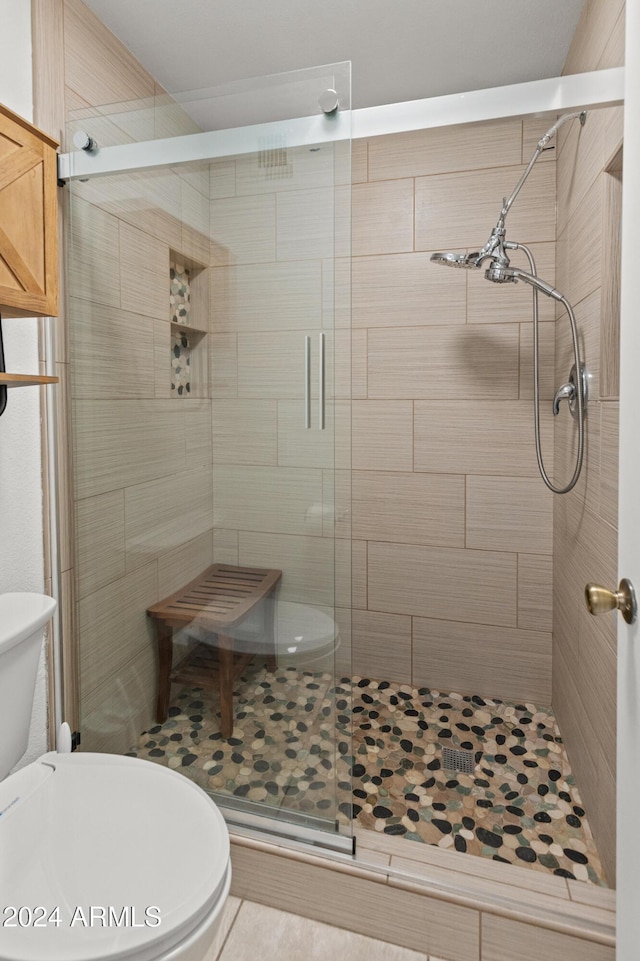 bathroom with toilet and a shower with door