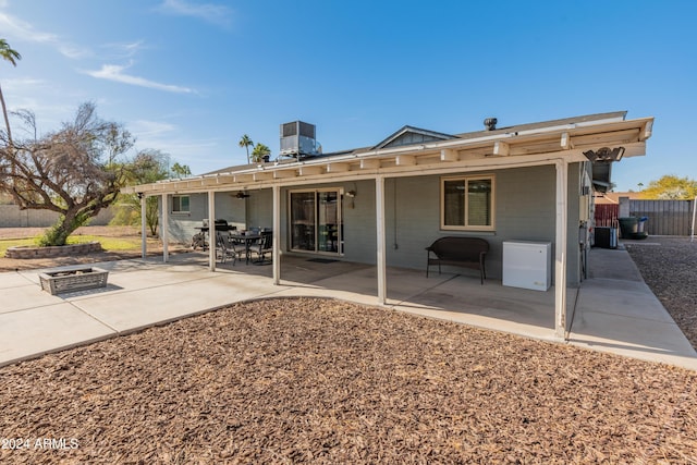 back of property with central air condition unit, a patio area, and a fire pit