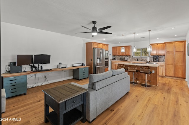 living room featuring sink, light wood-type flooring, and ceiling fan