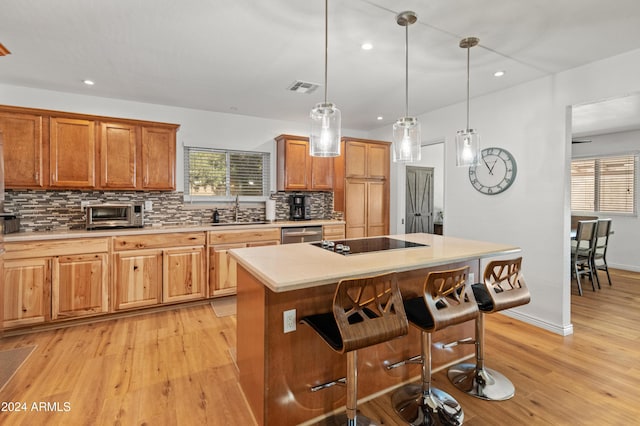 kitchen with sink, a center island, a breakfast bar area, decorative backsplash, and hanging light fixtures