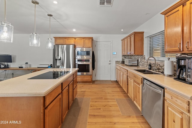 kitchen with sink, stainless steel appliances, a center island, and pendant lighting