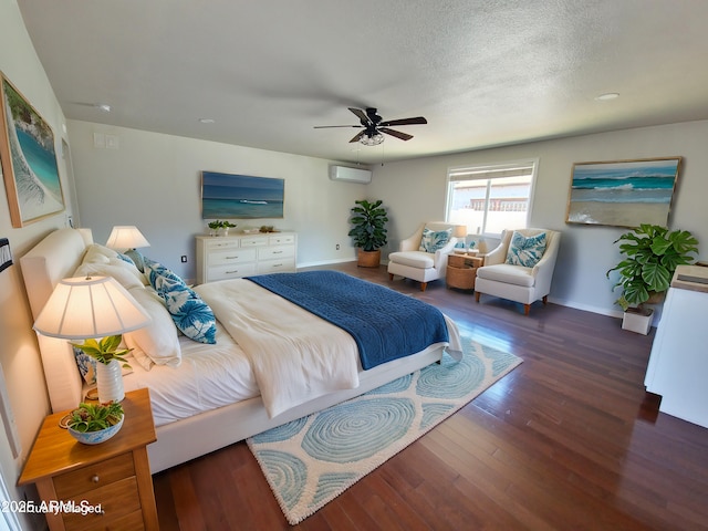 bedroom with dark wood-type flooring, ceiling fan, a wall mounted AC, and a textured ceiling