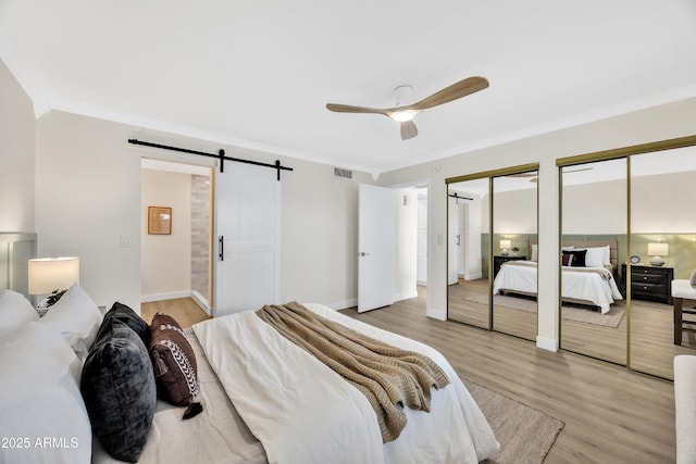 bedroom with crown molding, multiple closets, and a barn door