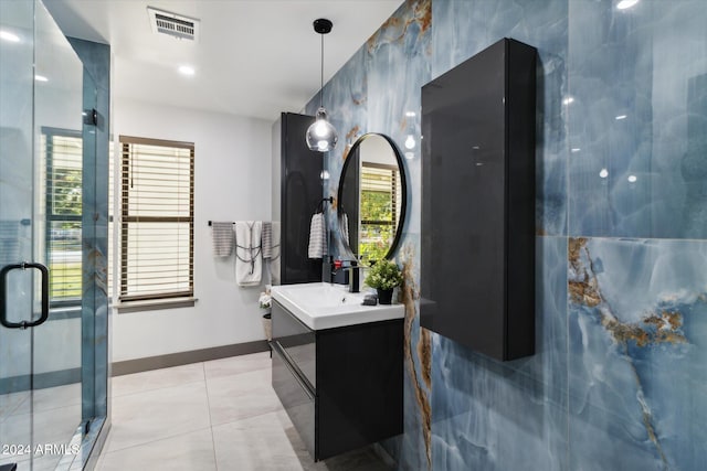 bathroom featuring tile patterned flooring, vanity, a healthy amount of sunlight, and a shower with shower door