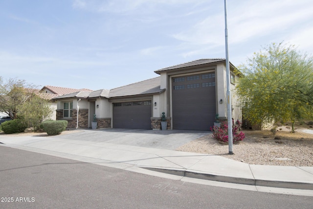 view of front of house featuring an attached garage, a tiled roof, stucco siding, driveway, and stone siding