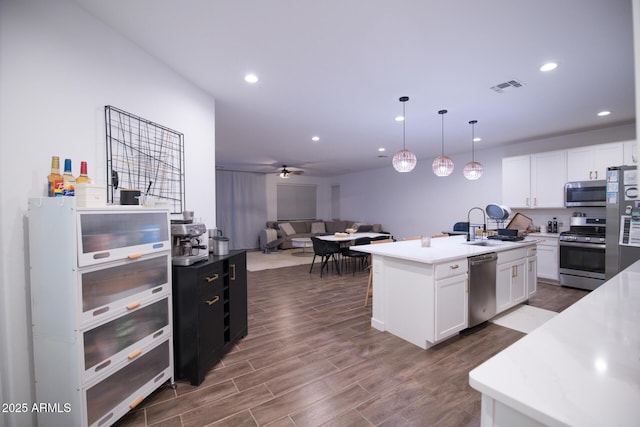 kitchen featuring stainless steel appliances, recessed lighting, a sink, white cabinetry, and dark wood-type flooring