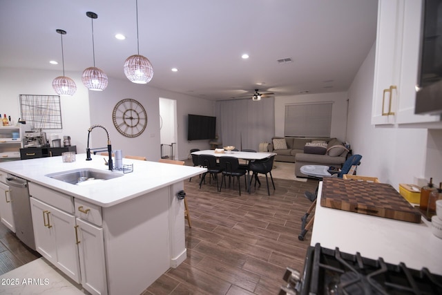 kitchen with a sink, a ceiling fan, wood tiled floors, white cabinets, and light countertops