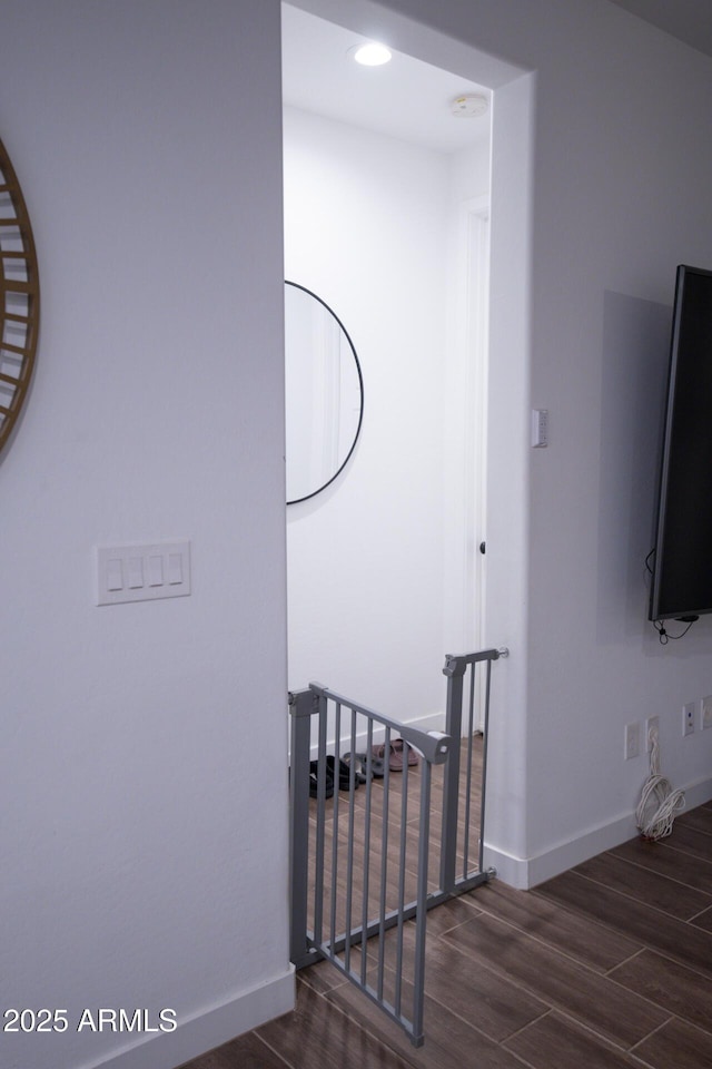 staircase featuring wood finished floors, baseboards, and recessed lighting