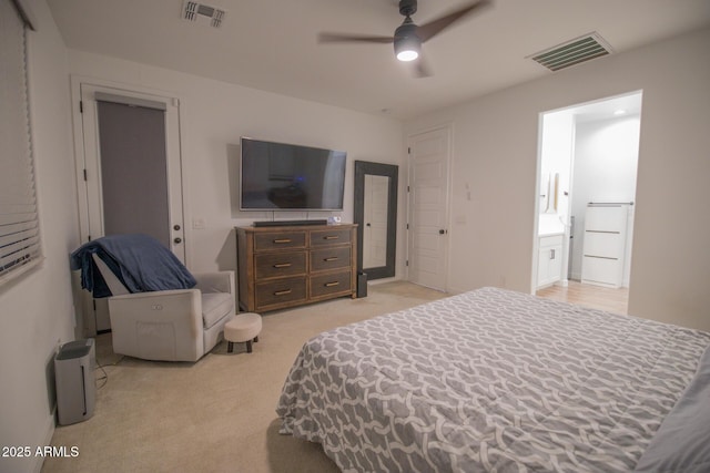 bedroom featuring light carpet, ensuite bathroom, and a ceiling fan