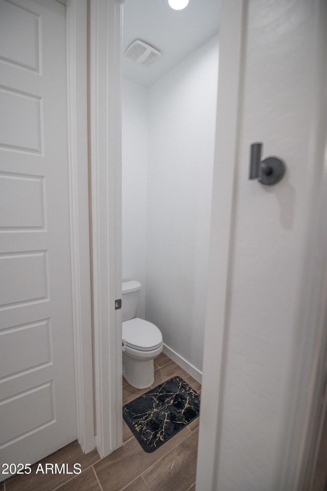 bathroom featuring wood finished floors and toilet
