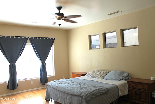 bedroom with light wood-style floors, baseboards, visible vents, and ceiling fan