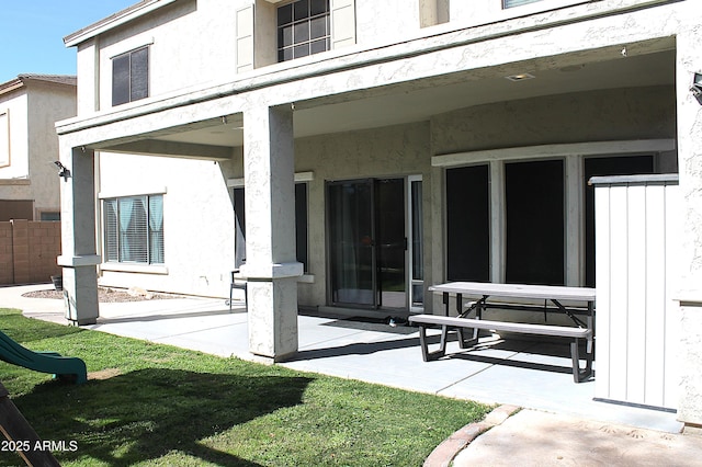 rear view of property with a lawn and stucco siding