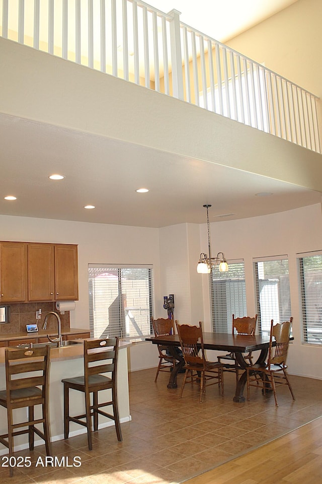 dining space with light wood-type flooring, recessed lighting, a towering ceiling, and a healthy amount of sunlight