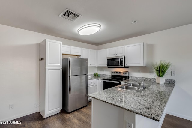 kitchen featuring kitchen peninsula, appliances with stainless steel finishes, dark wood-type flooring, sink, and white cabinets