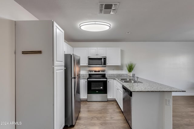 kitchen with sink, stainless steel appliances, light stone counters, light hardwood / wood-style flooring, and white cabinets