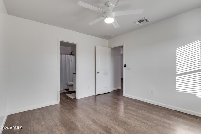 unfurnished bedroom featuring wood-type flooring, ensuite bathroom, and ceiling fan