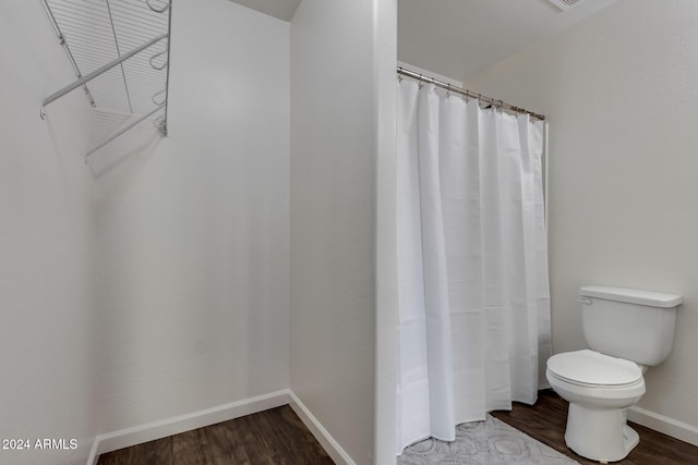 bathroom with hardwood / wood-style floors, curtained shower, and toilet