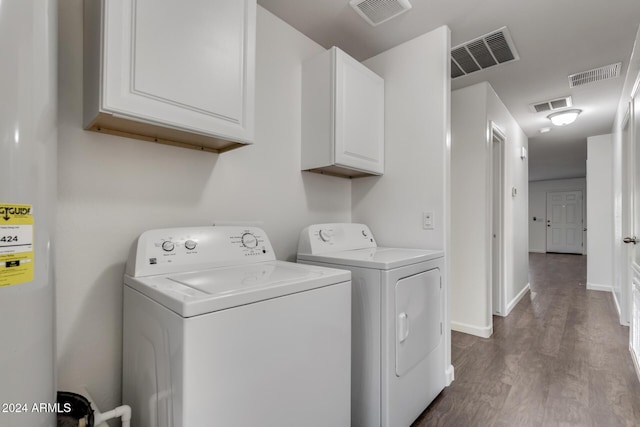 clothes washing area featuring cabinets, wood-type flooring, and washer and clothes dryer