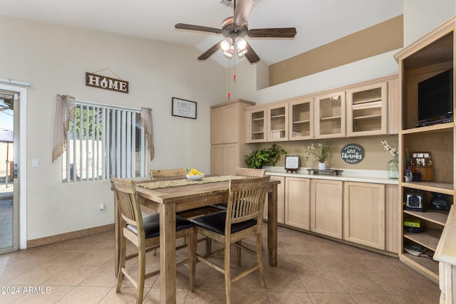 dining area with ceiling fan, vaulted ceiling, baseboards, and light tile patterned floors