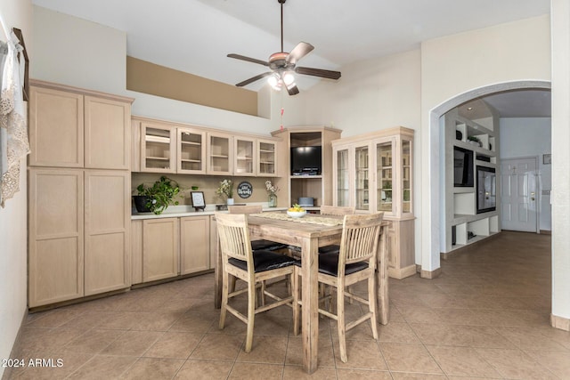 dining room with arched walkways, ceiling fan, light tile patterned floors, and a towering ceiling