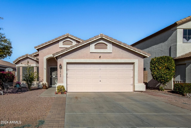 view of front of house featuring concrete driveway, an attached garage, a tiled roof, and stucco siding