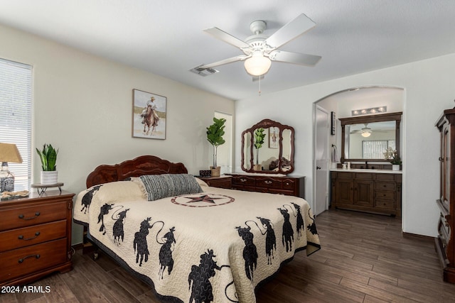 bedroom featuring a ceiling fan, arched walkways, dark wood finished floors, and ensuite bathroom