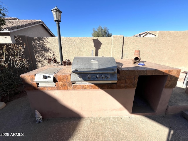 view of patio / terrace featuring a grill, an outdoor kitchen, and a fenced backyard